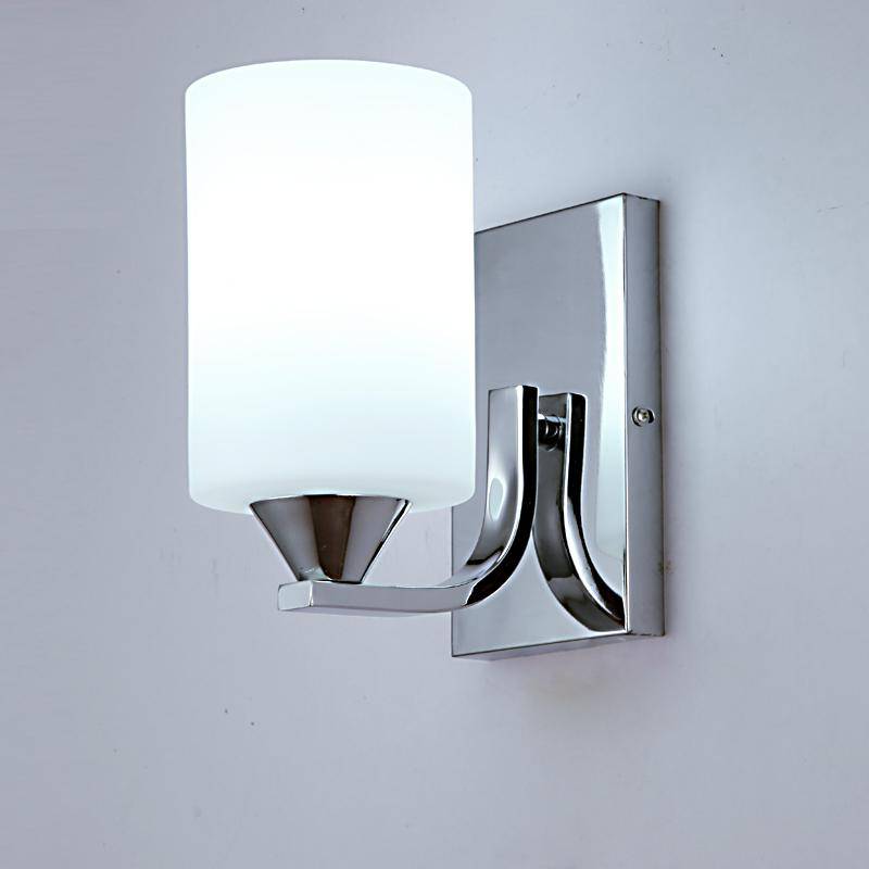 Lit chrome wall sconce casting a soft white glow on a grey wall