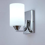 Lit chrome wall sconce casting a soft white glow on a grey wall