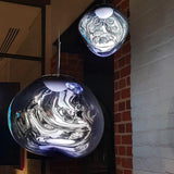 Chrome and blue toned molten pendants hanging against an exposed brick wall