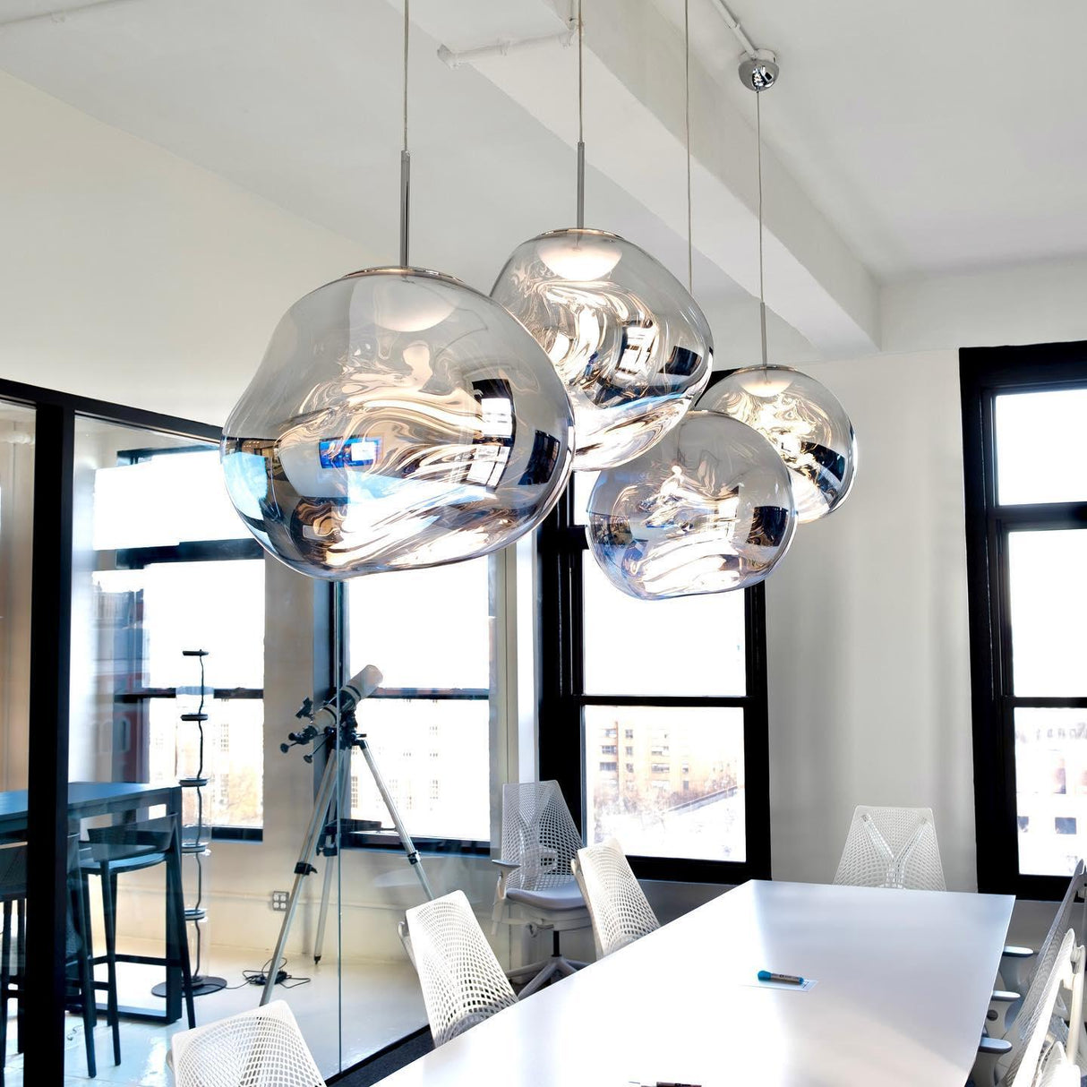 Chrome molten pendants above a bright kitchen bar with tall windows behind