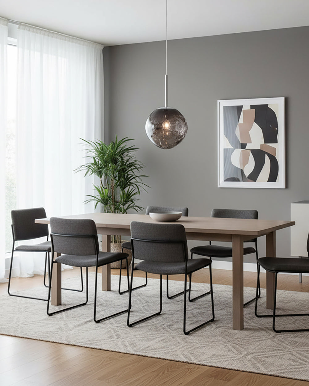 Chrome molten pendant hanging over a grey dining room table and six chairs