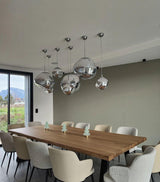 Cluster of chrome molten pendants suspended over a long timber dining table