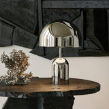 Chrome dome lamp lit on a live edge timber table against a dark wall