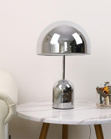 Chrome dome lamp on a round marble side table beside a cream armchair