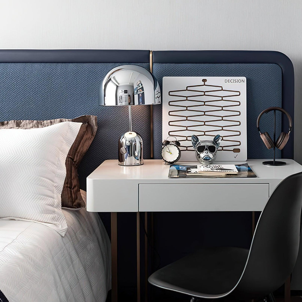 Chrome dome lamp on a white desk beside a blue upholstered headboard