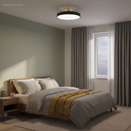 Black circular ceiling light above a bed in a green toned bedroom