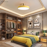 Yellow circular ceiling light in a bedroom with open timber wardrobe