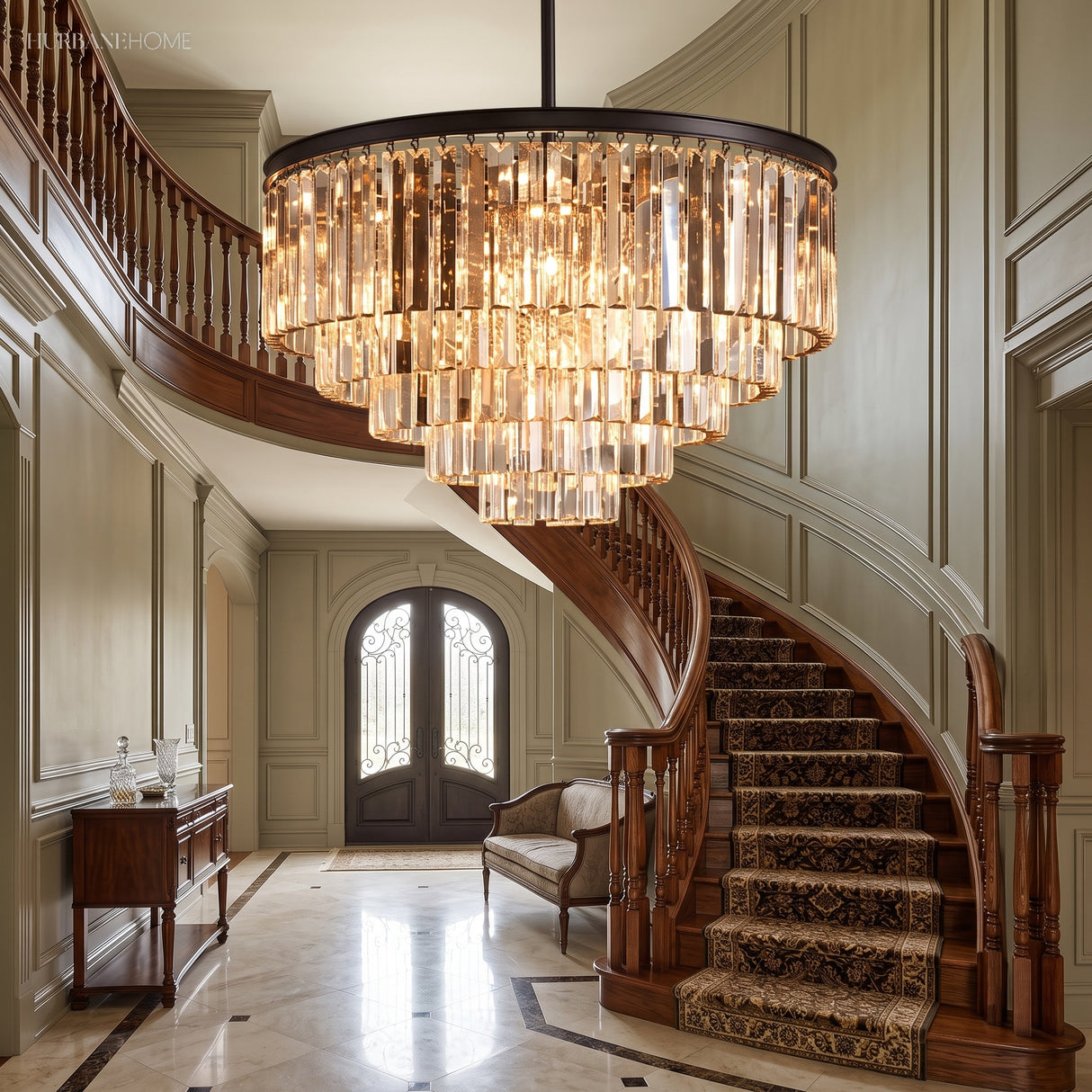 Clear crystal chandelier suspended above a curved staircase in a grand entryway