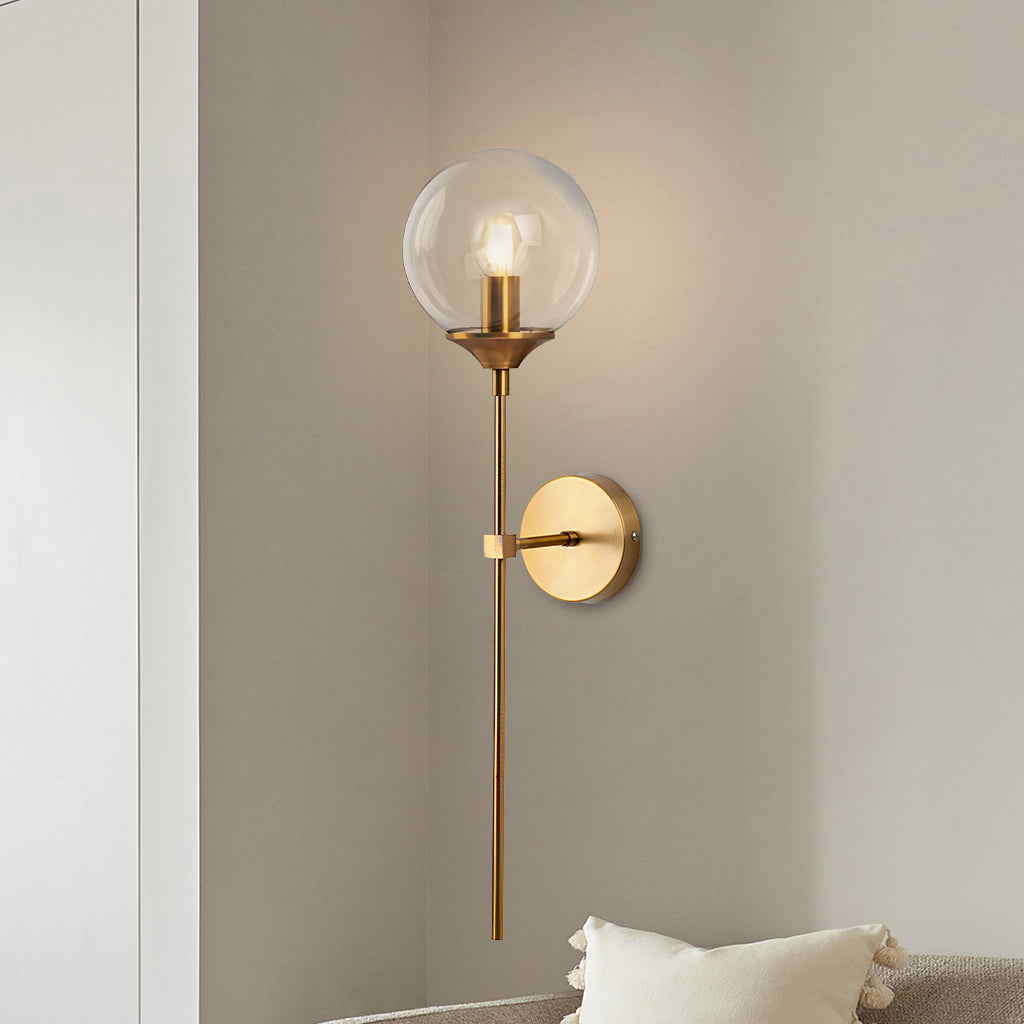 Clear glass globe wall sconce on a slim brass stem