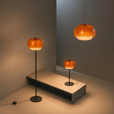 Rounded colored glass shade glowing softly above a slim metal lamp stem