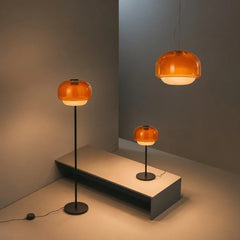 Rounded colored glass shade glowing softly above a slim metal lamp stem