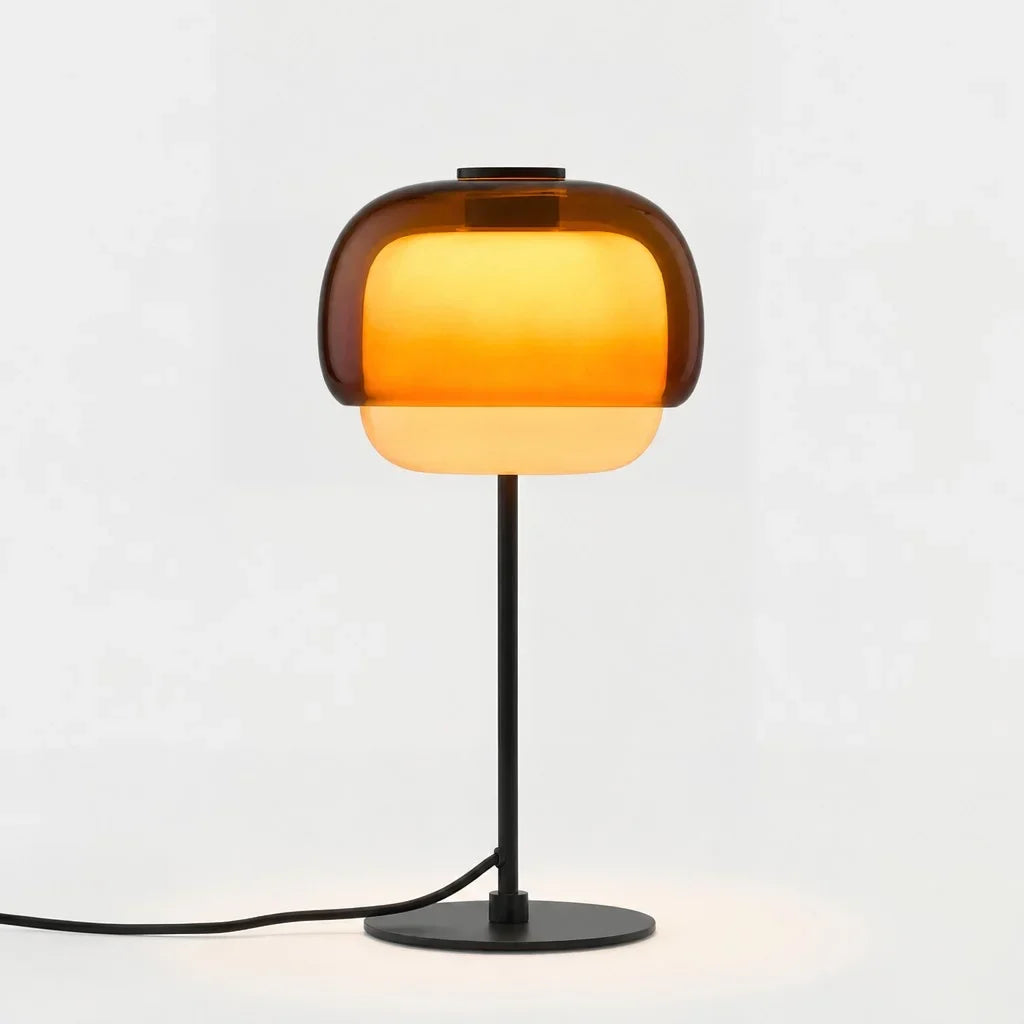 Amber domed glass table lamp with slim black stem and round metal base