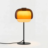 Amber domed glass table lamp with slim black stem and round metal base