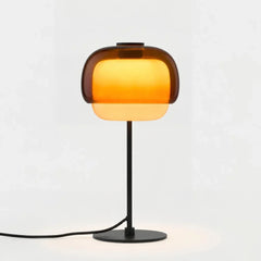 Amber domed glass table lamp with slim black stem and round metal base