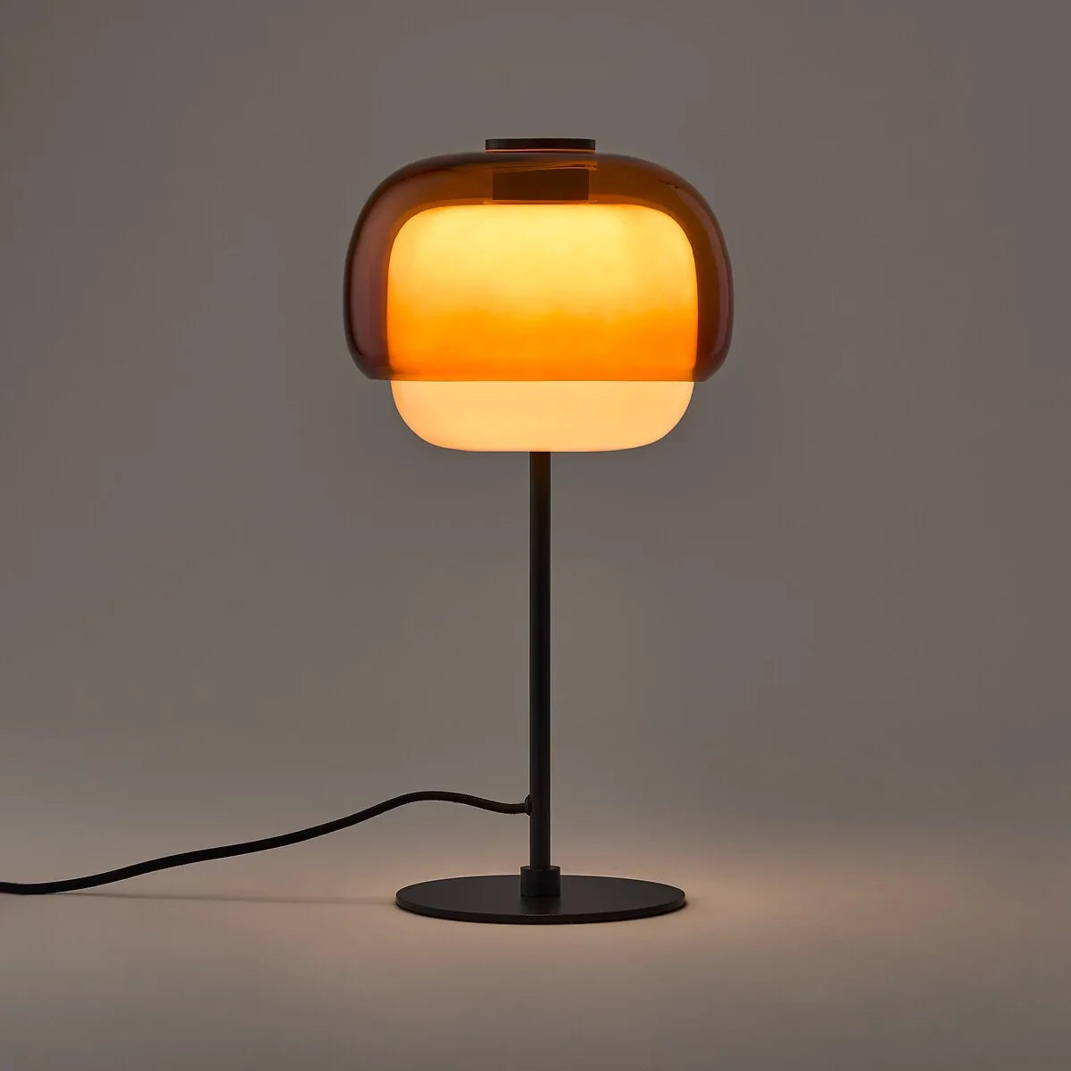 Orange colored glass table lamp with domed shade and round metal base