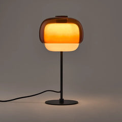 Orange colored glass table lamp with domed shade and round metal base