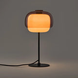 Pink colored glass table lamp with rounded shade on a metal stem