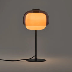 Pink colored glass table lamp with rounded shade on a metal stem