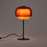 Red colored glass table lamp with domed shade and dark metal base