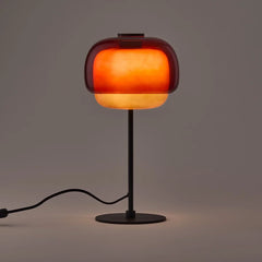 Red colored glass table lamp with domed shade and dark metal base