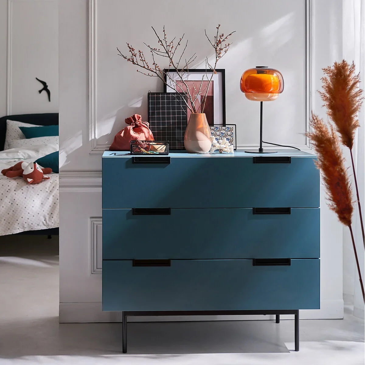 Colored glass table lamp styled on a surface within a decorated room scene
