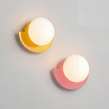 Yellow colorful glass globe wall sconce shown against a neutral backdrop