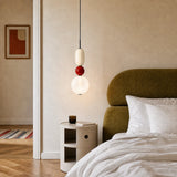 Glass pendant light with red disc and rounded jars on a plain background
