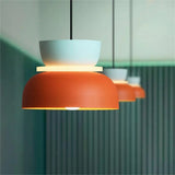 Row of light blue and orange pendants against a green fluted wall