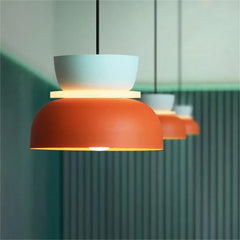 Row of light blue and orange pendants against a green fluted wall