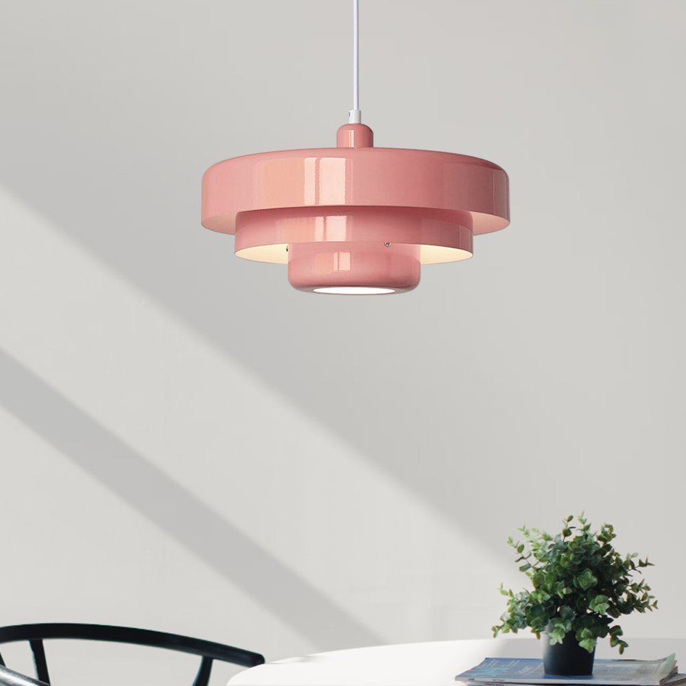 Pink tiered pendant light throwing soft shadows on a sunlit white wall