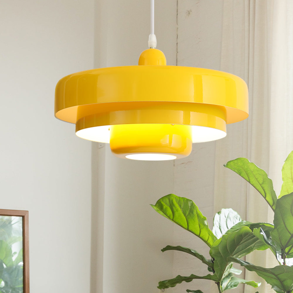 Yellow tiered pendant light hanging by a bright window next to a leafy plant