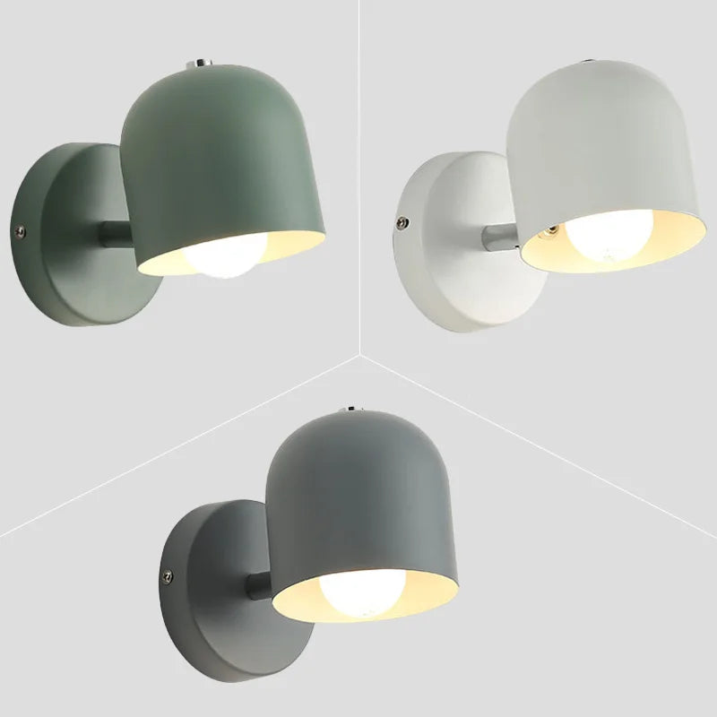 White macaron sconce lit above a bedside cabinet and alarm clock