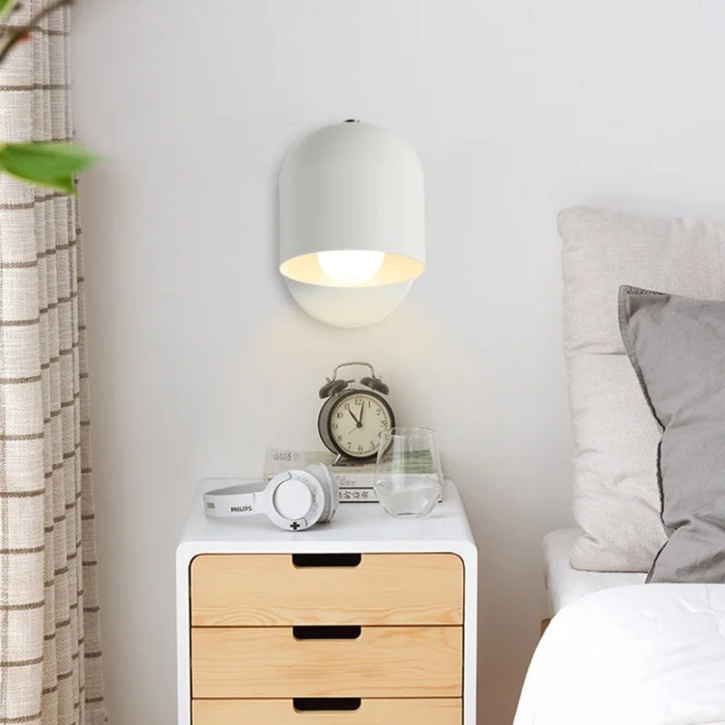 Grey dome wall sconce lit above a bed with a record print behind
