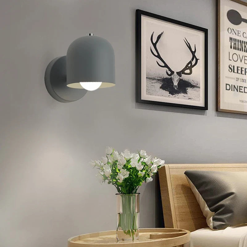 White dome sconce lit above a bed with a yellow throw