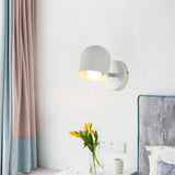 Grey macaron sconce lit above a wooden bedside table