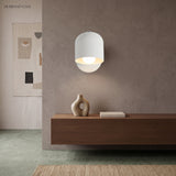 White dome wall sconce lit over a walnut console and vases