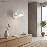 White dome sconce lit above a sideboard beside a potted olive tree