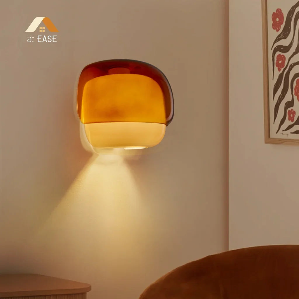 Lit coloured glass sconce glowing softly against a textured painted wall