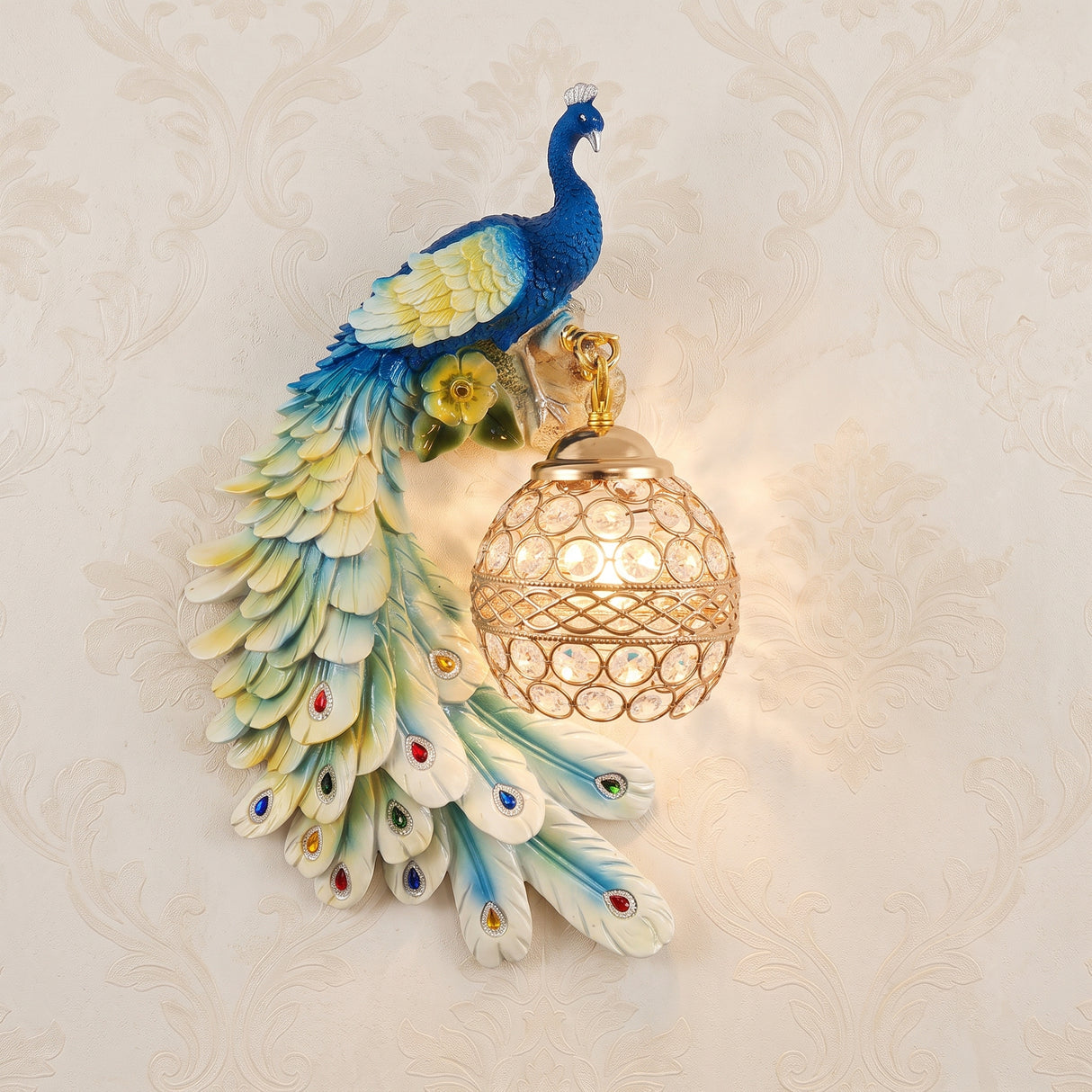 Colourful blue and green resin peacock wall sconce holding a lit crystal ball shade