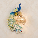 Colourful blue and green resin peacock wall sconce holding a lit crystal ball shade