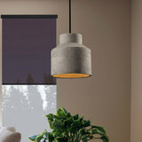 Cylinder cement pendant beside a window with a dark blind