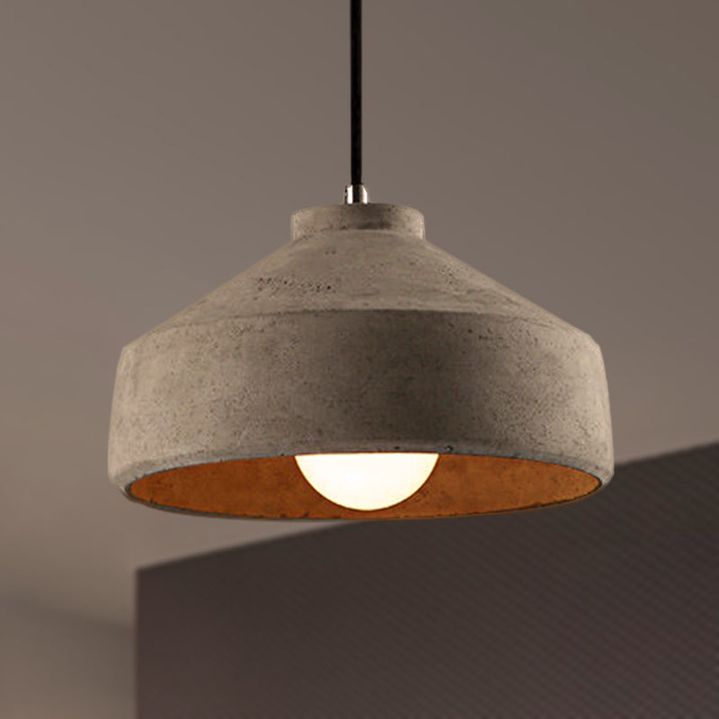 Wide cement dome pendant lit above a dark counter edge