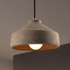 Wide cement dome pendant lit above a dark counter edge
