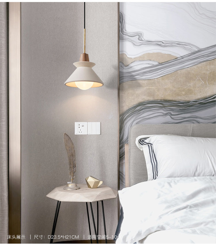 Cement pendant lit beside a bed on a marble patterned wall