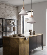Two cone pendants above a brass kitchen island by a brick wall