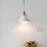 Cone pendant lit above a flower arrangement on a grey wall