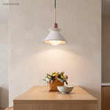 White cement pendant glowing above a wooden table with flowers
