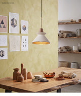 Cement cone pendant over a timber table against a yellow wall
