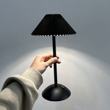 Hand holding the slim black cordless table lamp by its stem