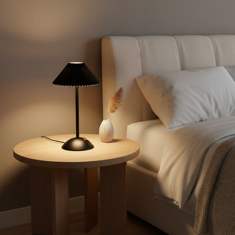 Hand holding the slim black cordless table lamp by its stem